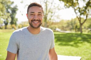 A relaxed, smiling middle-aged man outdoors in a park, representing everyday mens health and wellbeing.