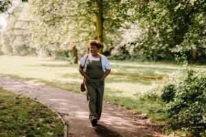 A person walking on a sunlit park path, representing a long-term everyday approach to weight management.