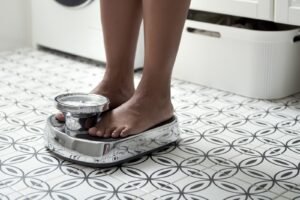 Bare feet stepping onto a bathroom scale, representing tracking progress during medical weight management.