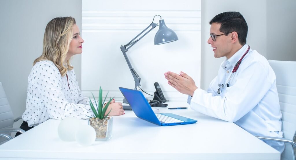 A patient talking with a licensed provider across a desk during a consultation.
